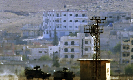 The black Isis banner atop a building in Kobani, taken from over the Turkish-Syrian border. The armo