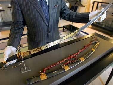 ** FILE ** French auctioneer Jean-Pierre Osenat presents a gold-encrusted sword Napoleon wore into battle in Italy in June 1800, in this May 25, 2007 file photo taken in Paris. The last of Napoleon's swords in private hands, it has an estimated value of euro1.2 million to euro1.5 million (USD1.6 million to USD2 million). The Osenat auction house, managing the sale, said it may sell for two to three times that amount. It will be auctioned off Sunday, June 10, 2007 across the street from one of Napoleon's imperial castles in Fontainebleau, south of Paris. (AP Photo/Remy de la Mauviniere, file)