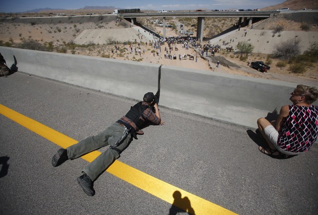 Eric Parker from central Idaho aims his weapon from a bridge as protesters gather by the Bureau of Land Management's base camp, where cattle that were seized from rancher Cliven Bundy are being held, near Bunkerville, Nevada April 12, 2014. The U.S. Bureau of Land Management on Saturday said it had called off an effort to round up Bundy's herd of cattle that it had said were being illegally grazed in southern Nevada, citing concerns about safety. The conflict between Bundy and U.S. land managers had brought a team of armed federal rangers to Nevada to seize the 1,000 head of cattle.