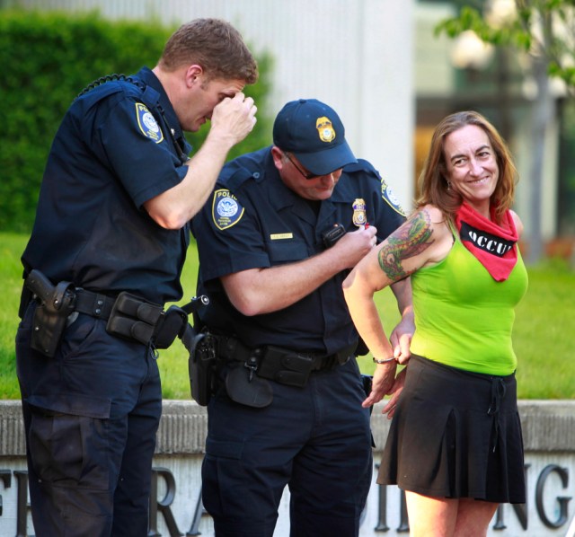 FILE-This July 10, 2012, file photo shows Occupy Eugene member Emily Semple, right, smiling as she is placed under arrest by Federal Police after she refused to leave the outdoor plaza at the Federal Courthouse in Eugene, Ore. (AP Photo/The Register-Guard, Chris Pietsch, File)
